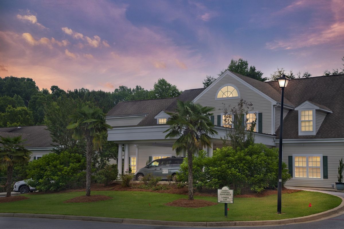 A suburban house with well-maintained landscaping set against a sunset sky.