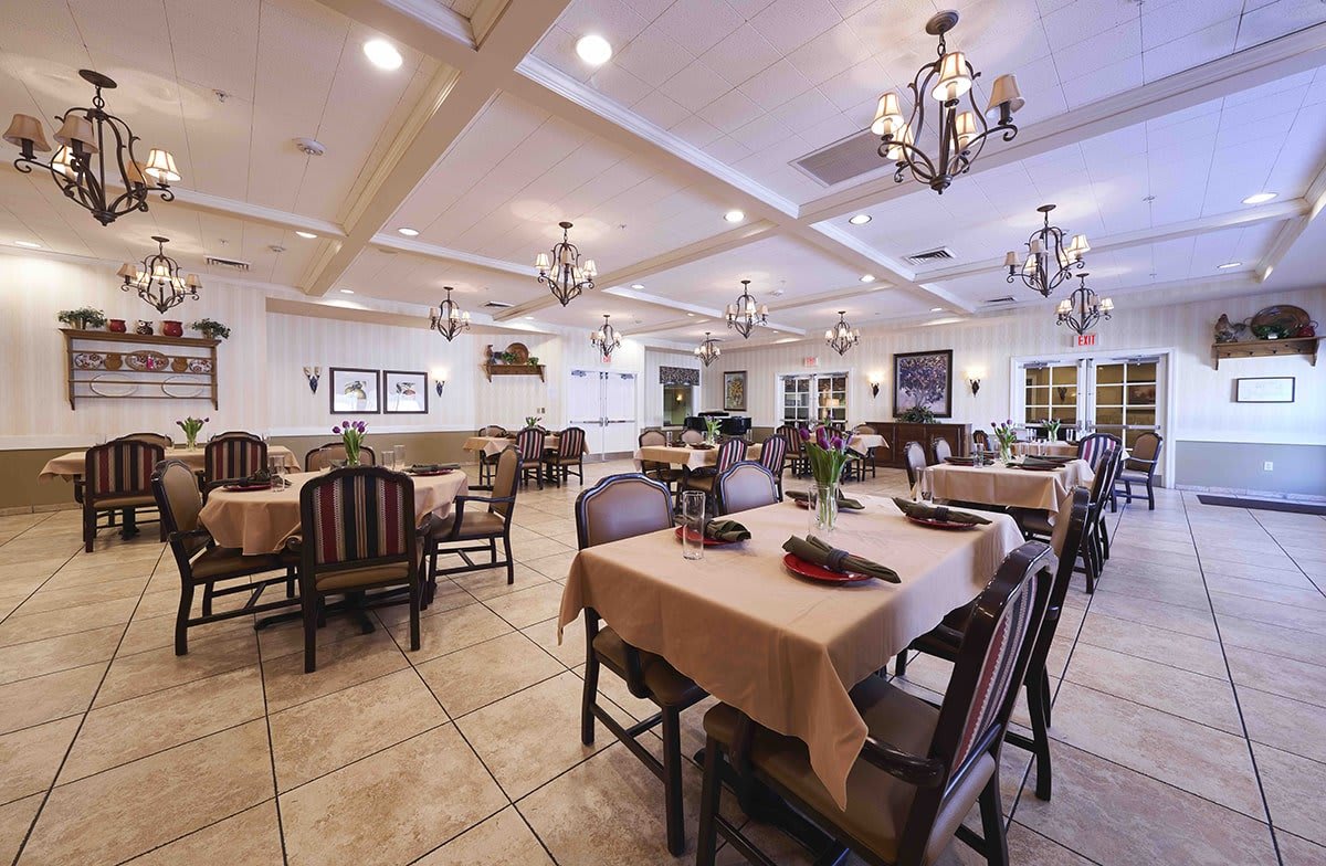 A spacious dining area with neatly arranged tables and elegant chandeliers.