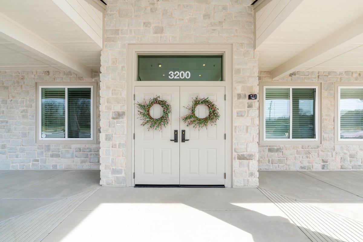 A building entrance with double doors adorned with wreaths and the number 2020.