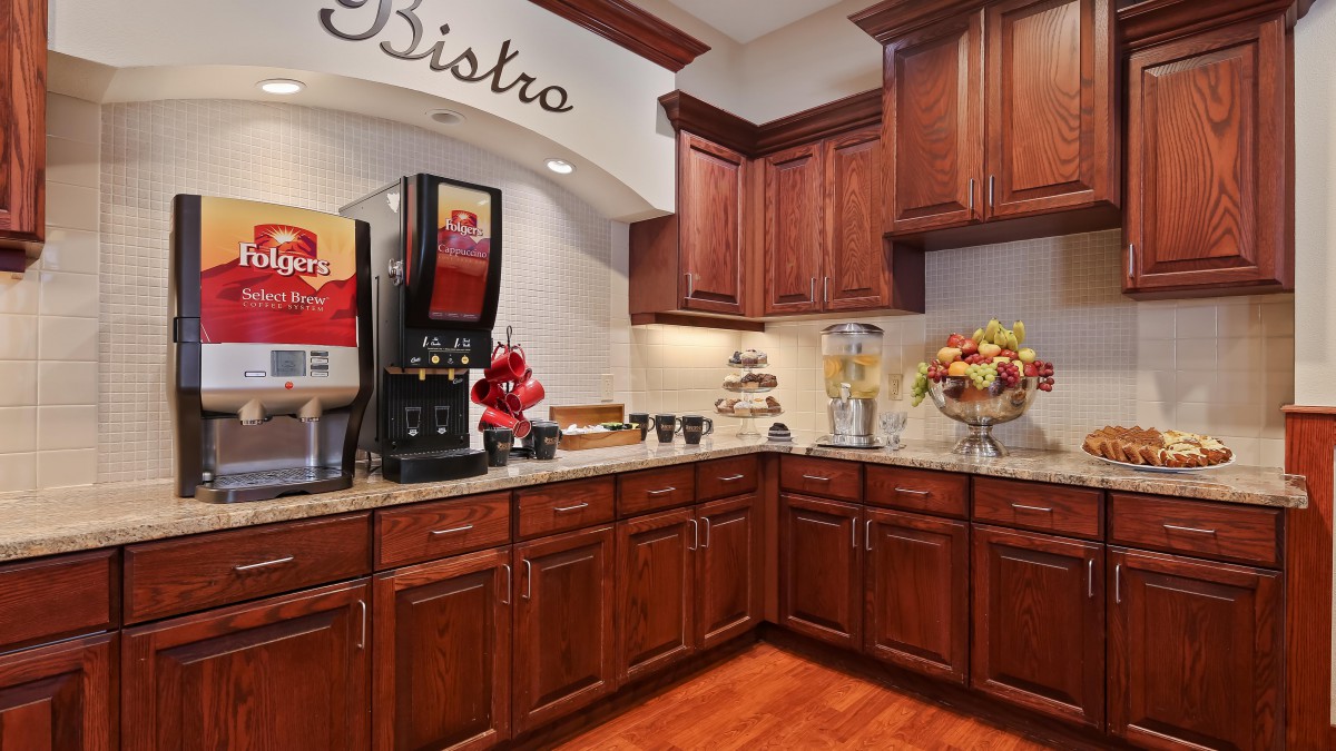 A cozy bistro kitchen corner with a coffee machine and wooden cabinets.