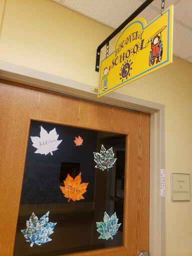 A decorated classroom door featuring autumn-themed leaf cutouts and a welcoming sign.