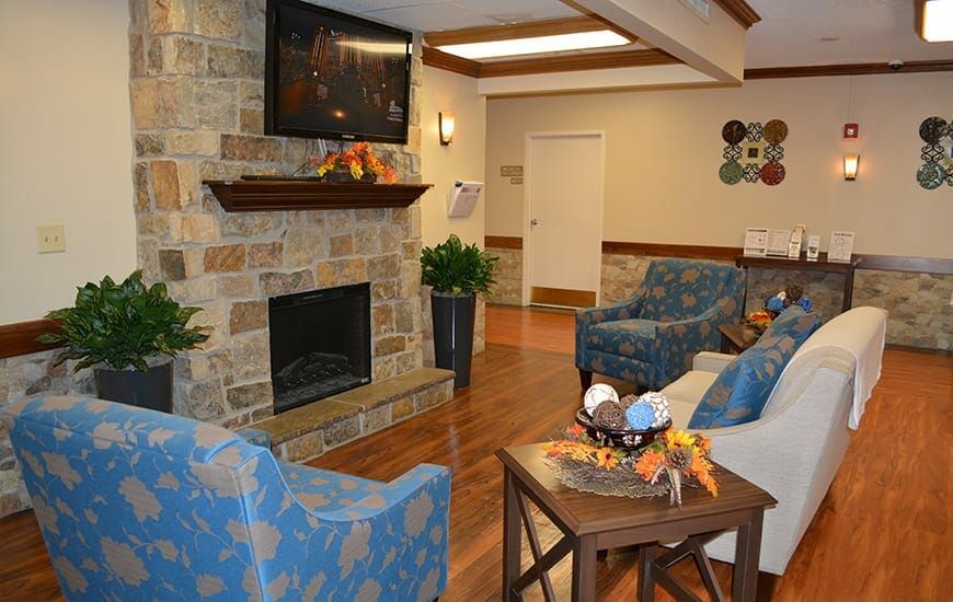 A cozy living room with a stone fireplace, television, and comfortable seating.