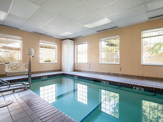 An indoor swimming pool surrounded by large windows allowing natural light to fill the space.