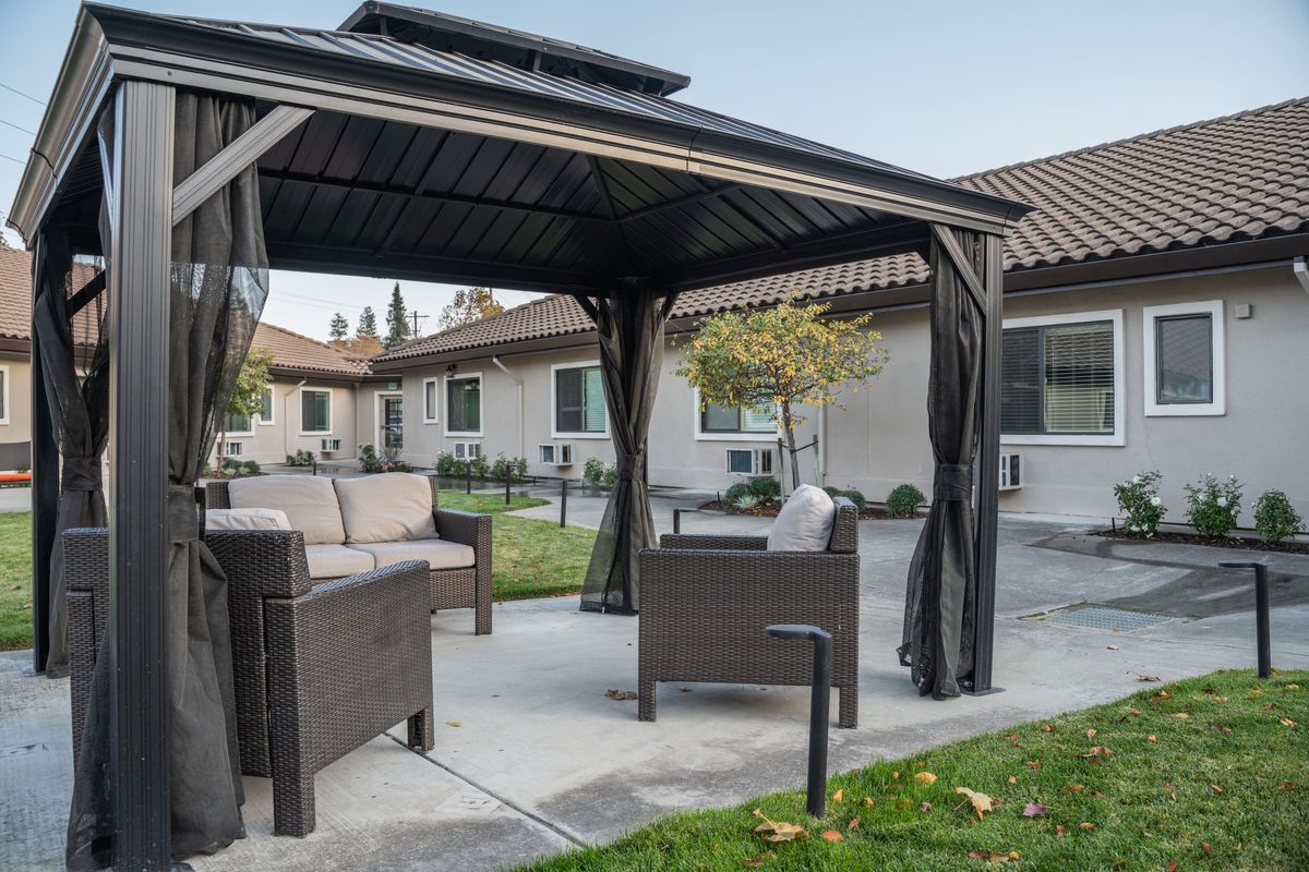 A cozy outdoor gazebo with comfortable seating in a backyard setting.