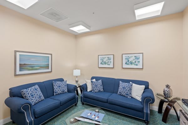 A cozy living room with blue sofas and wall art.