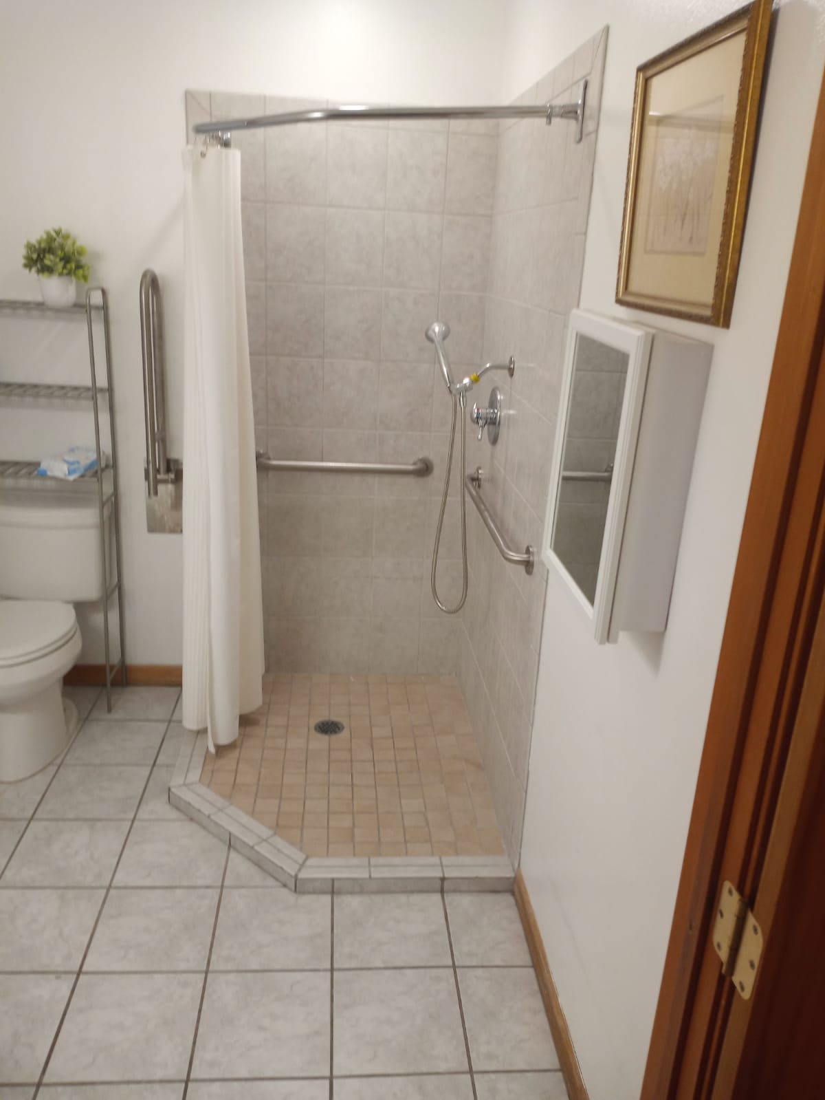 A bathroom with a walk-in shower, grab bar, and tiled floor.