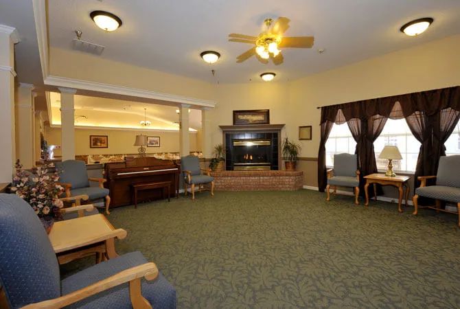 A cozy living room featuring comfortable chairs, a fireplace, and a ceiling fan.