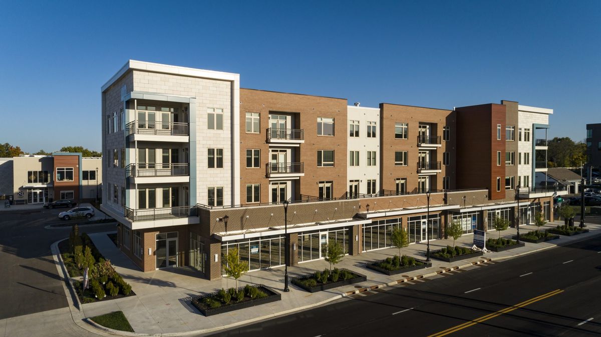 A modern residential apartment building with retail storefronts on the ground floor.