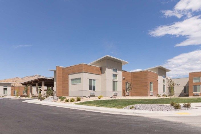 A modern suburban residential building with clean lines and landscaped surroundings under a clear blue sky.
