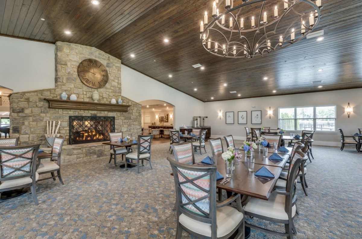 A spacious dining room with a rustic design, featuring a large fireplace and elegant chandelier.