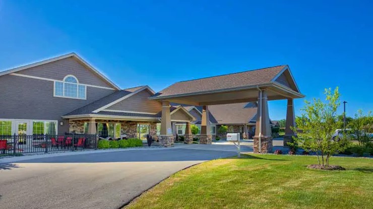 A modern residential building with a driveway and well-maintained landscaping under a clear blue sky.