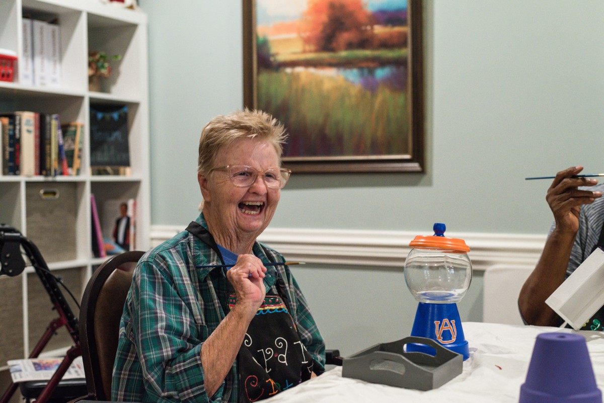 A person smiling happily while sitting indoors with a game on the table.