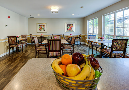 A cozy dining area featuring a bowl of fresh fruits on the table, surrounded by neatly arranged tables and chairs.