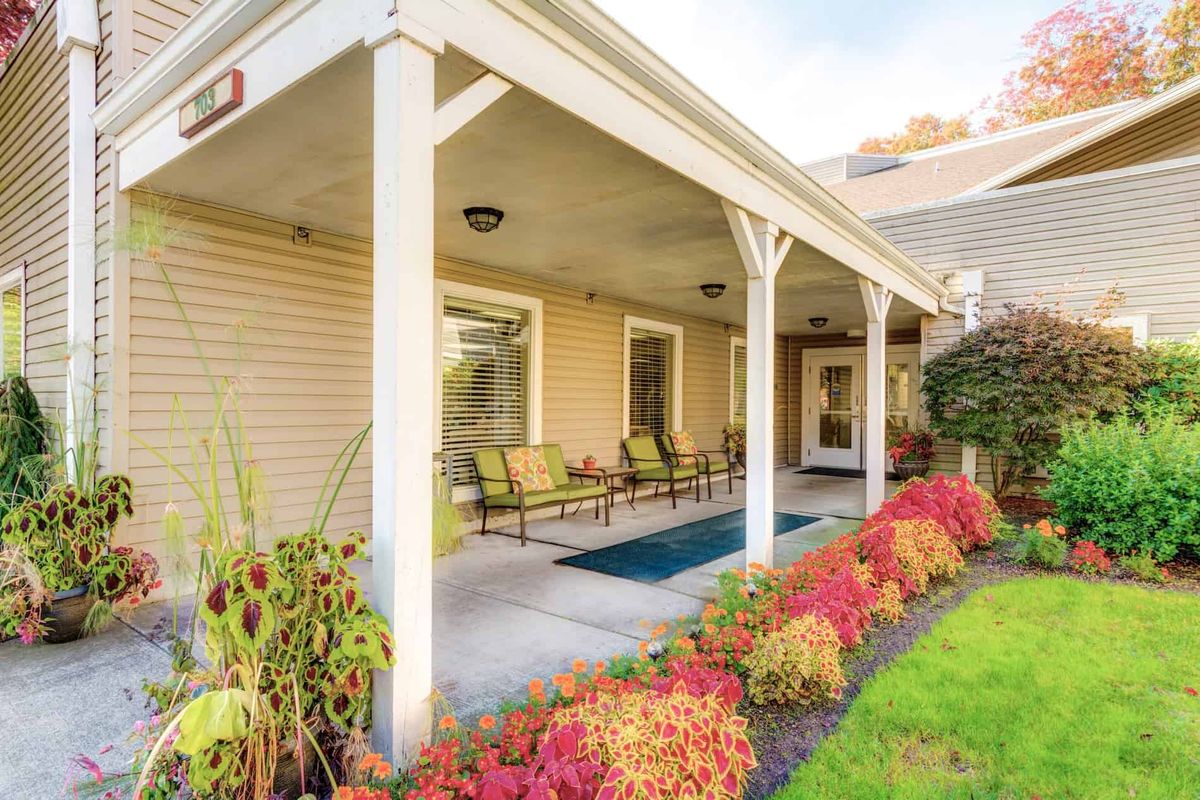 A cozy porch with comfortable chairs and vibrant garden landscaping.