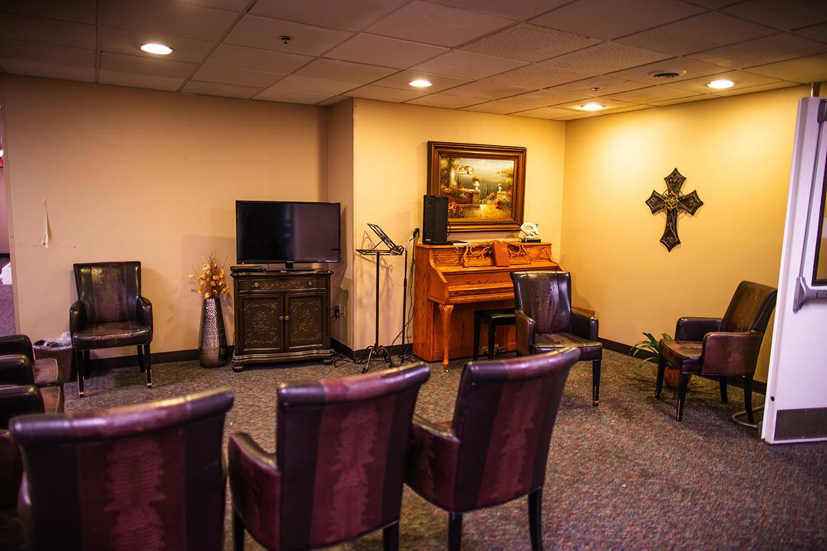 A cozy room with chairs, a television, and a piano under warm lighting.