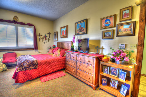 A cozy and inviting bedroom featuring a red bedspread, wooden furniture, and decorative wall art.