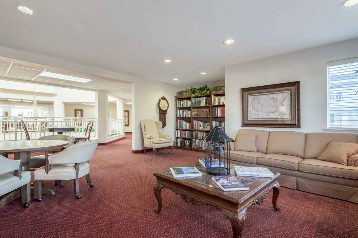 A cozy living room with comfortable seating, a bookshelf, and a traditional pendulum clock.