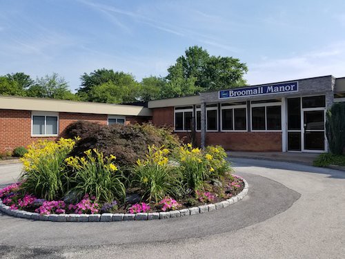 The entrance of a school building with well-maintained landscaping and colorful flowers.