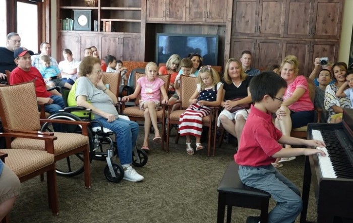 A group of adults and children seated indoors, attentively watching an event or performance.