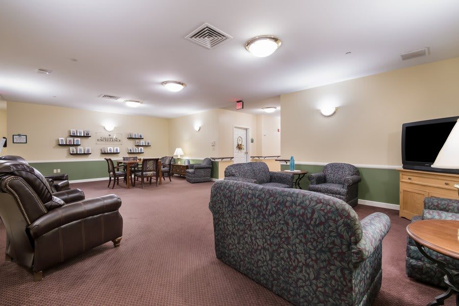 A cozy living room featuring comfortable seating and a dining table, elegantly lit with ceiling lights.