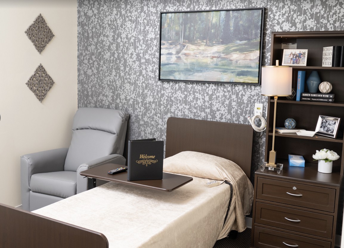 A cozy bedroom with a single bed, side table, armchair, and decorative wall art.