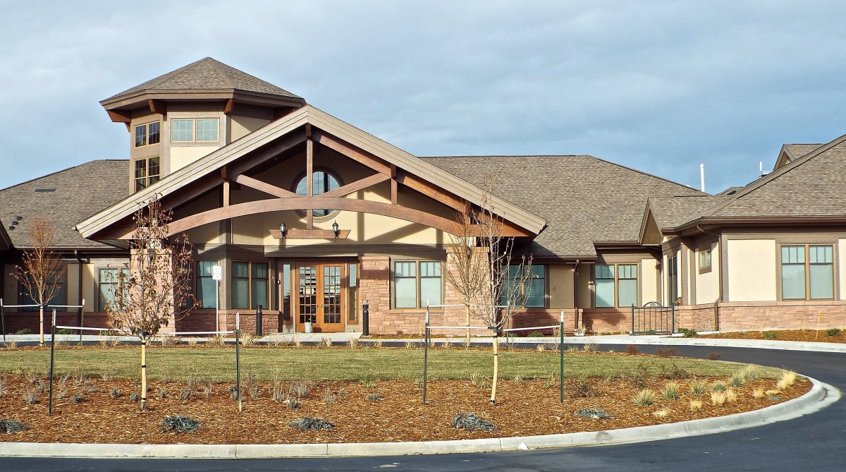 A large building with a gabled roof and extensive landscaping in front.