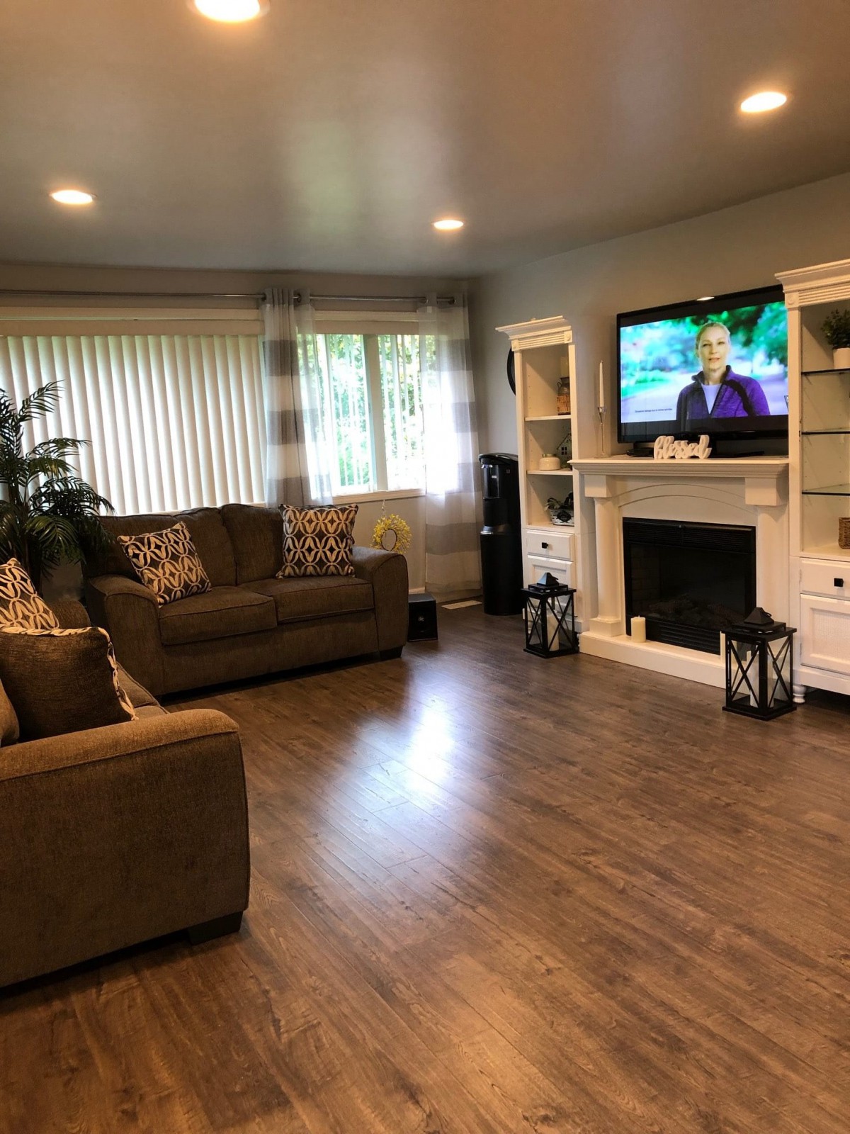 A cozy living room with a sofa, television, and fireplace on hardwood floors.