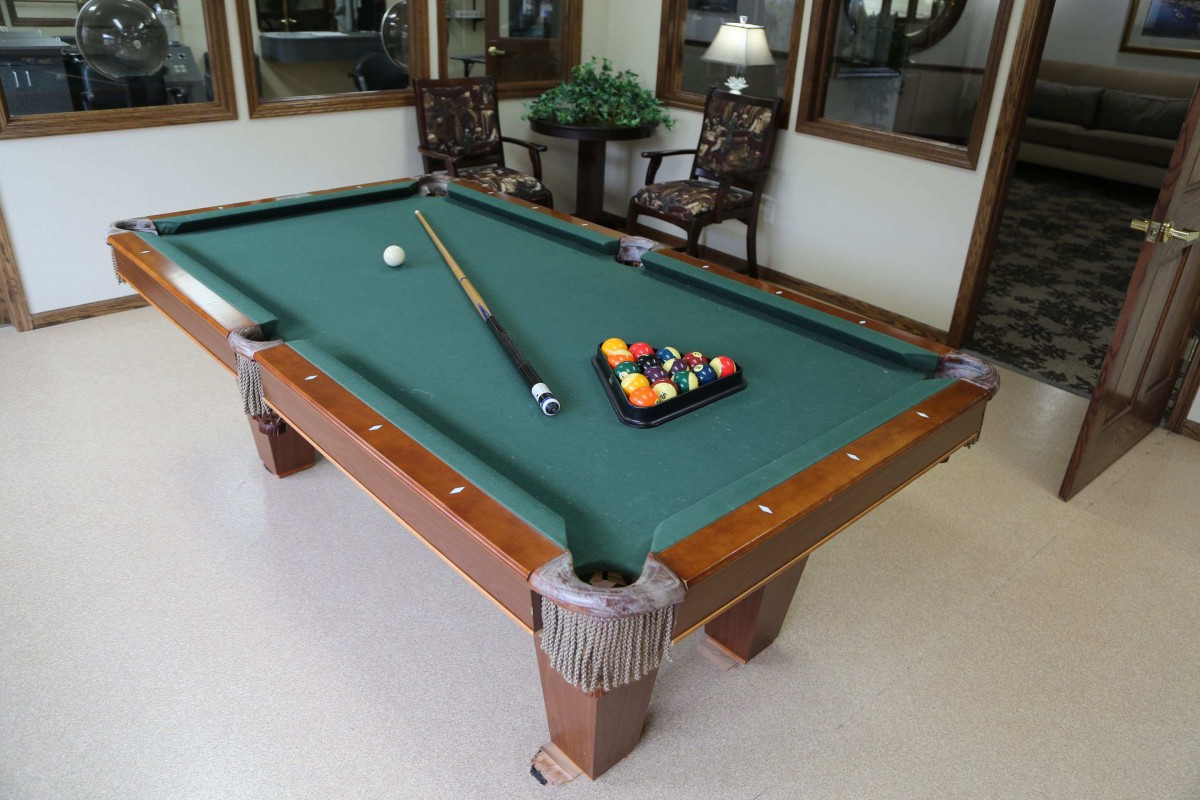 A pool table set up with a cue stick and a rack of billiard balls, ready for play.