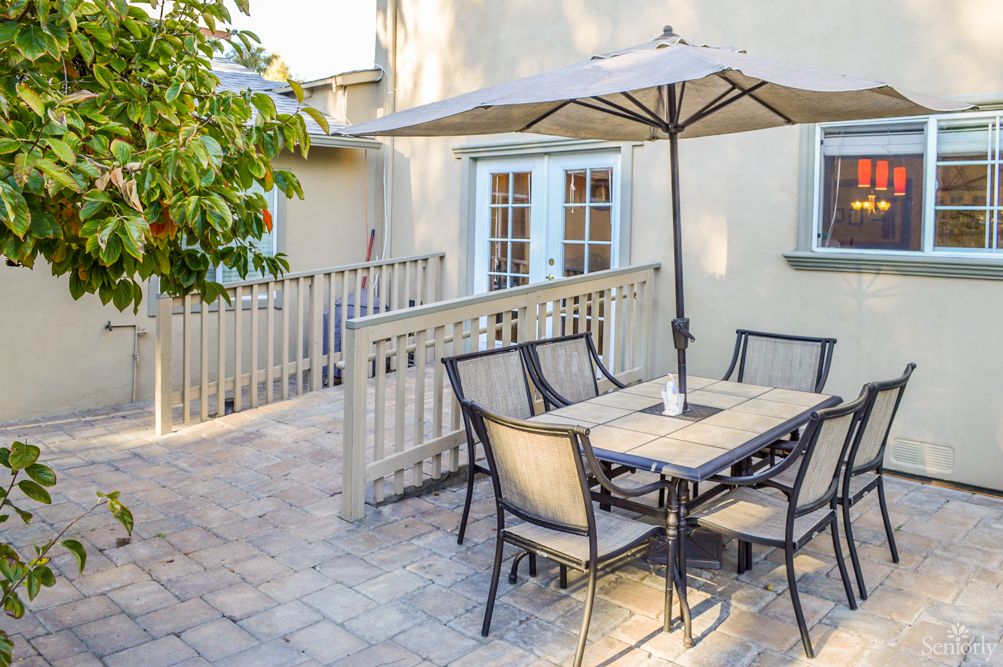 A cozy outdoor patio with a dining set and umbrella, perfect for enjoying sunny weather.