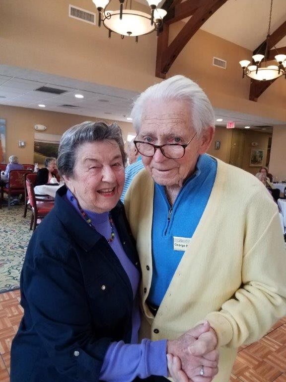 An elderly couple smiling and enjoying their time together indoors.
