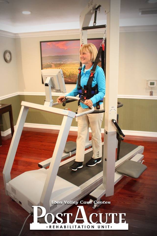 A person using a treadmill with a support harness for rehabilitation.
