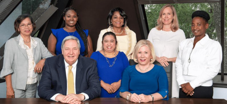 A diverse group of individuals in formal attire posing for a business portrait.