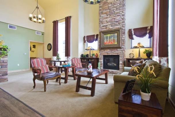 A cozy living room with a high ceiling and a central fireplace, featuring comfortable seating and elegant decor.