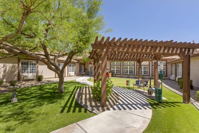 A serene courtyard with a wooden pergola and lush greenery.