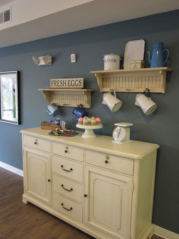 A cozy kitchen nook featuring shelves with mugs, decorative jars, and a vintage cabinet.