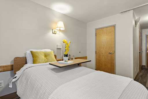 A cozy and modern bedroom featuring a comfortable bed with yellow accents and a bedside table.