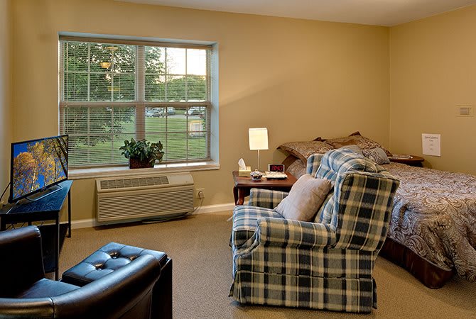 A cozy living room with an armchair, side table, and a large window letting in natural light.