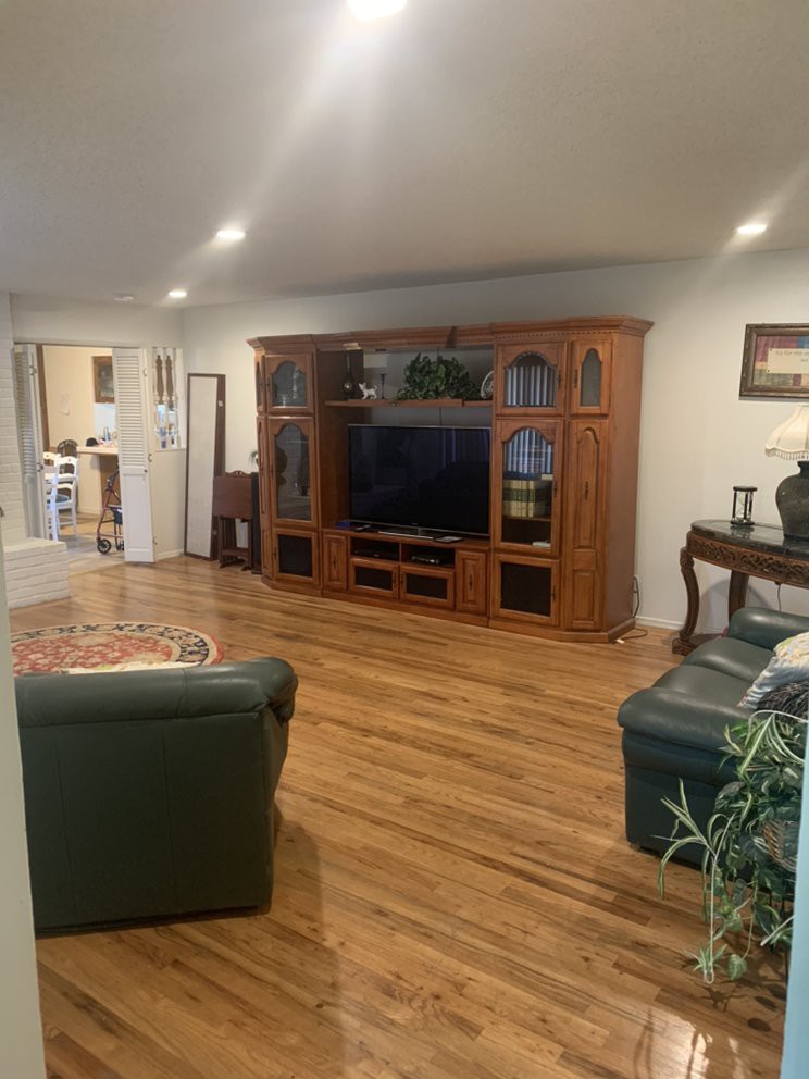 A cozy living room with a wooden entertainment center, television, and comfortable seating.