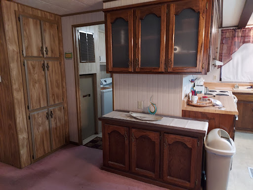 A view of a vintage kitchen featuring wooden cabinets and essential appliances.