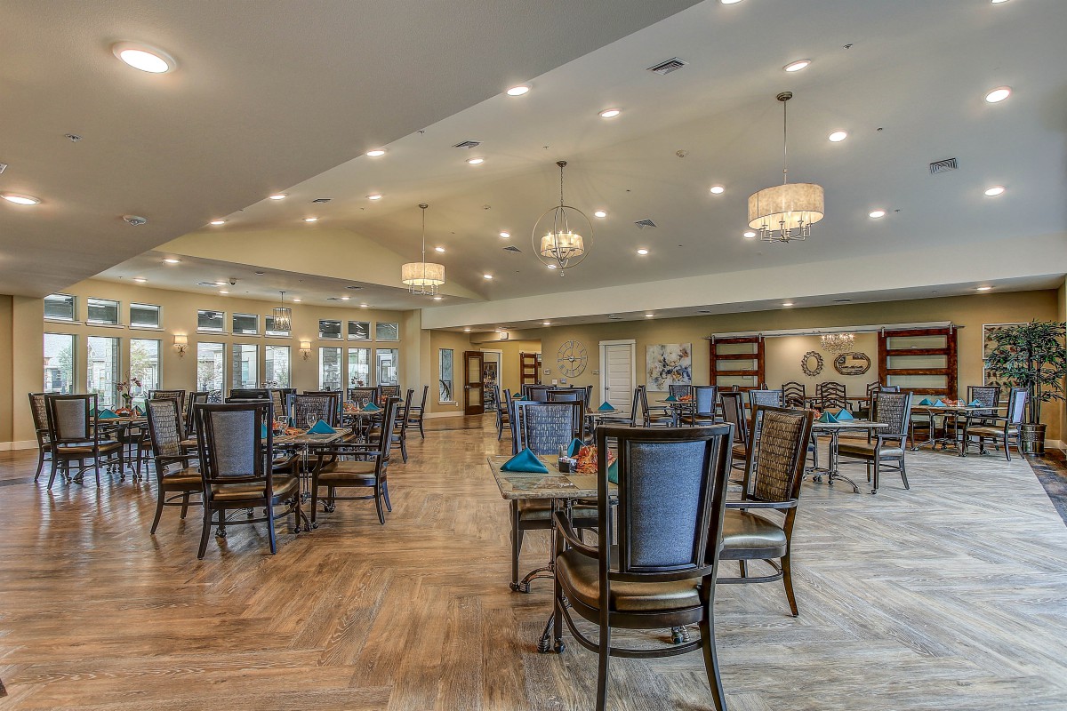 A spacious and elegantly designed dining area with well-arranged tables, chairs, and ambient lighting.