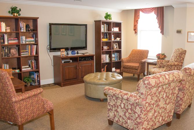 A cozy living room with a television, bookshelves, and comfortable seating.