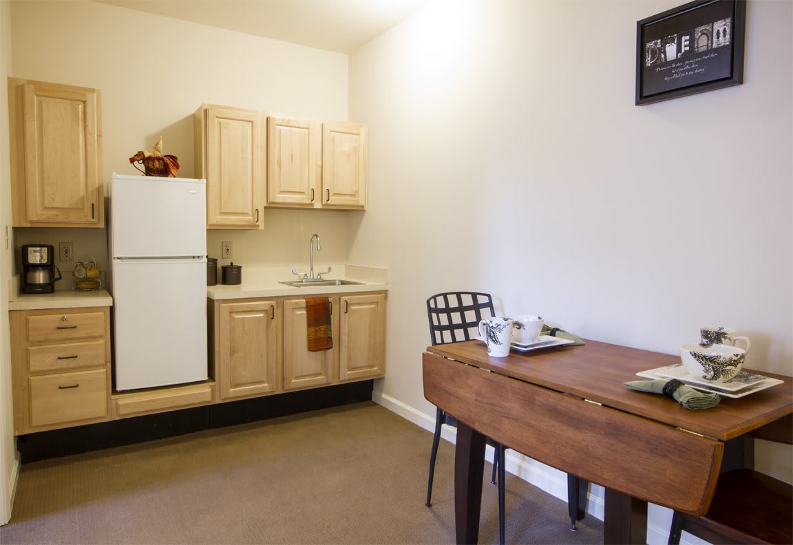 A cozy kitchen and dining area featuring wooden cabinets and a simple table with chairs.