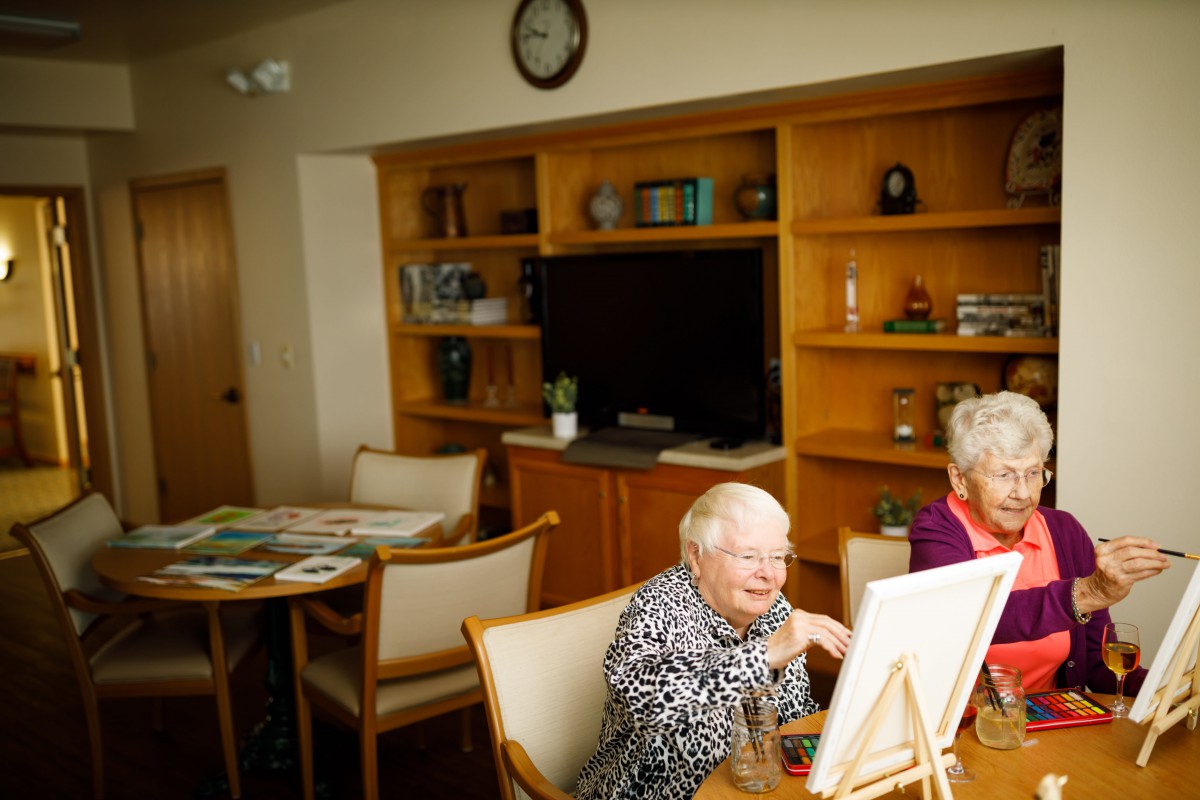 Elderly women enjoying a painting session in a cozy room.