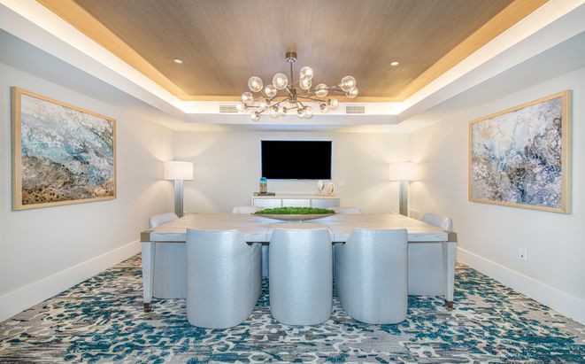 A modern conference room with a sleek chandelier and decorative carpet.