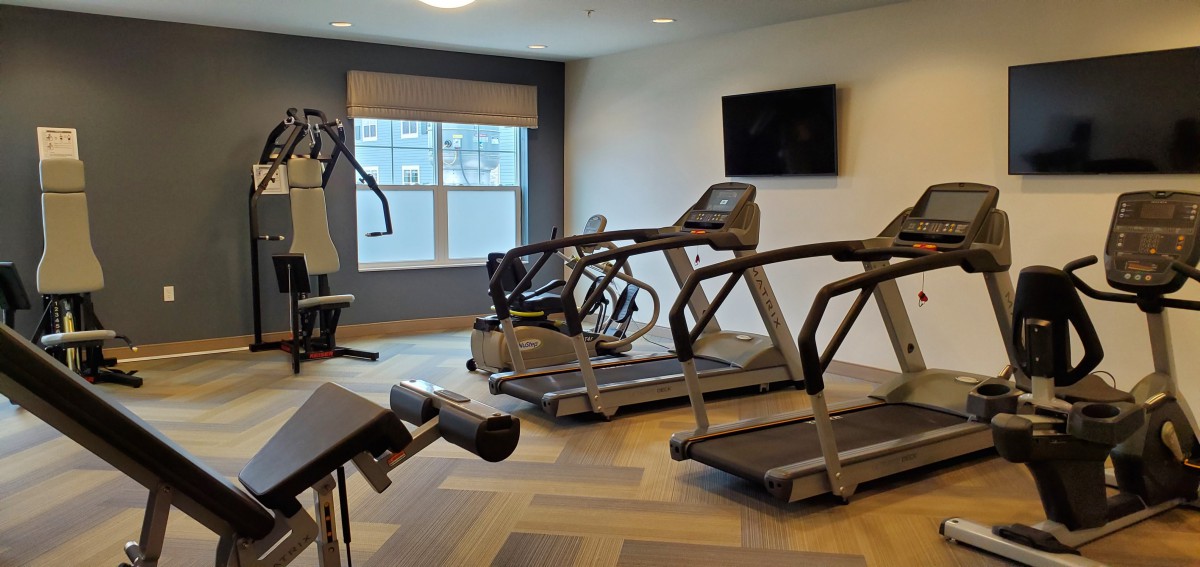 A modern gym with treadmills, a stationary bike, and other exercise equipment.