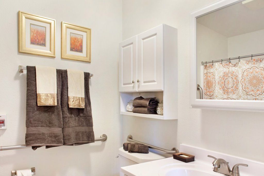 A neatly organized bathroom with wall-mounted cabinets, towels, and decorative elements.