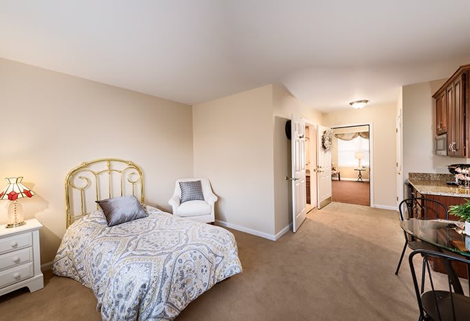 A minimalist bedroom featuring a single bed, a chair, and neutral-toned decor.