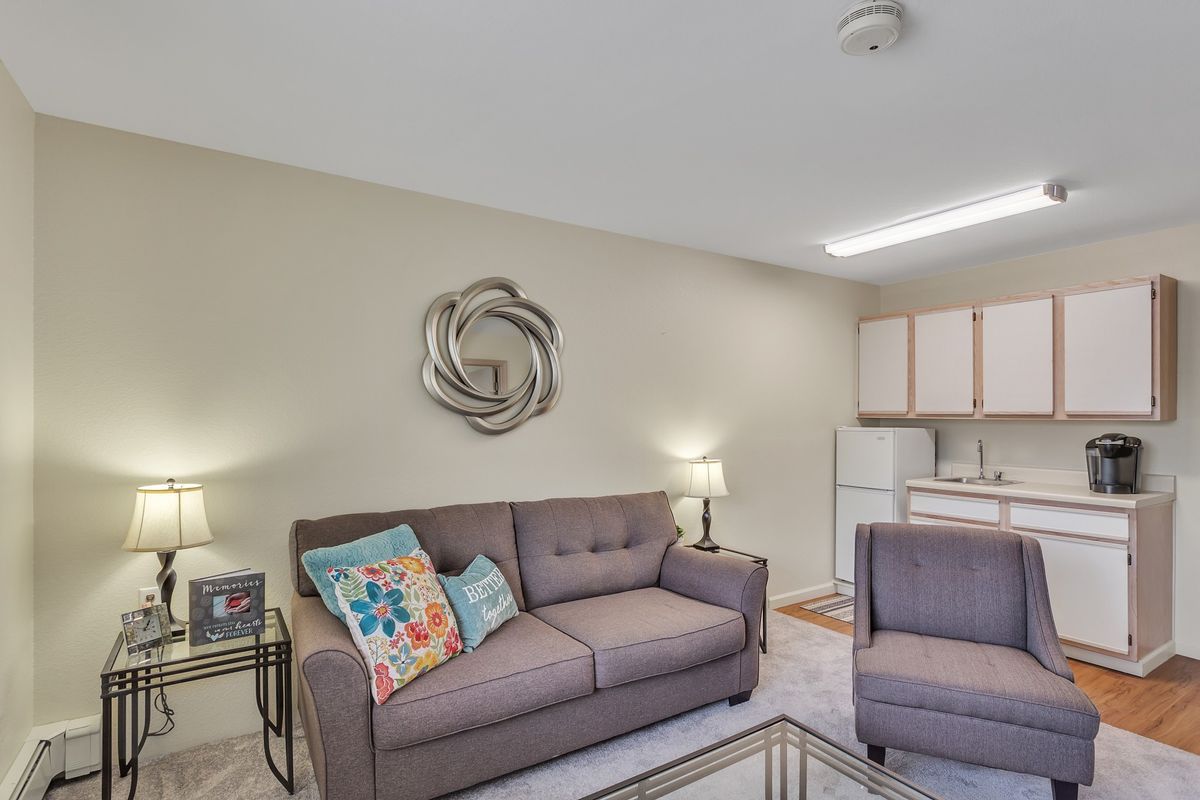 A cozy living room with a comfortable sofa and decorative pillows adjacent to a kitchen area.