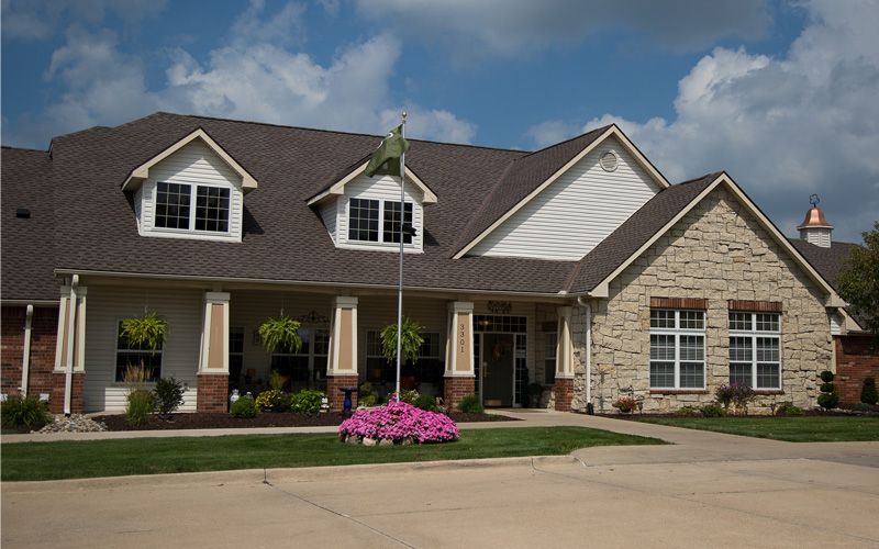 A suburban house with a landscaped front yard and a driveway under a cloudy sky.