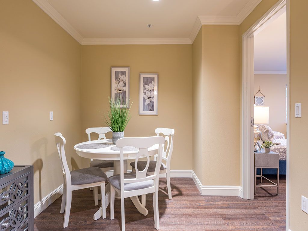 A cozy dining area featuring a round table with chairs, complemented by an indoor plant and wall art.